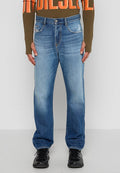 Blaue Straight-Leg-Jeans mit ausgewaschenen Stellen, fünf Taschen und Knopfverschluss, kombiniert mit einem braunen Langarmoberteil und schwarzen Sneakers.