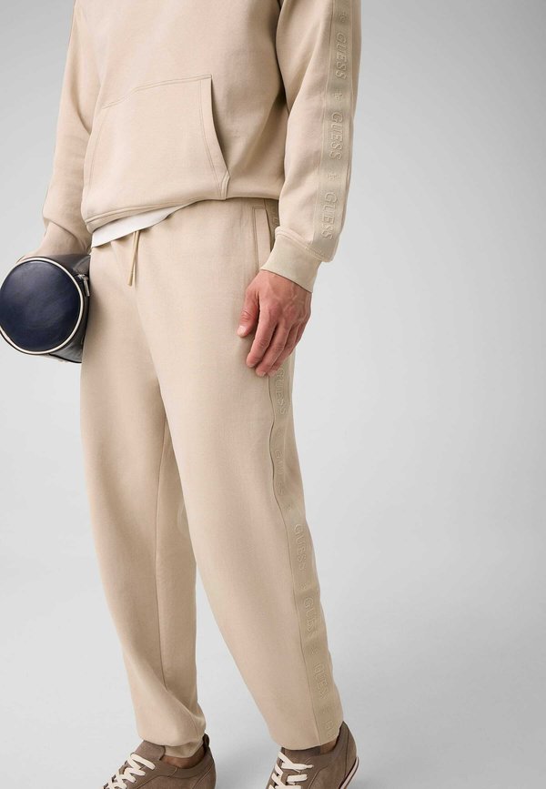 Guess JOGGINGHOSE MIT SEITLICHEM LOGO - Tracksuit bottoms - beige