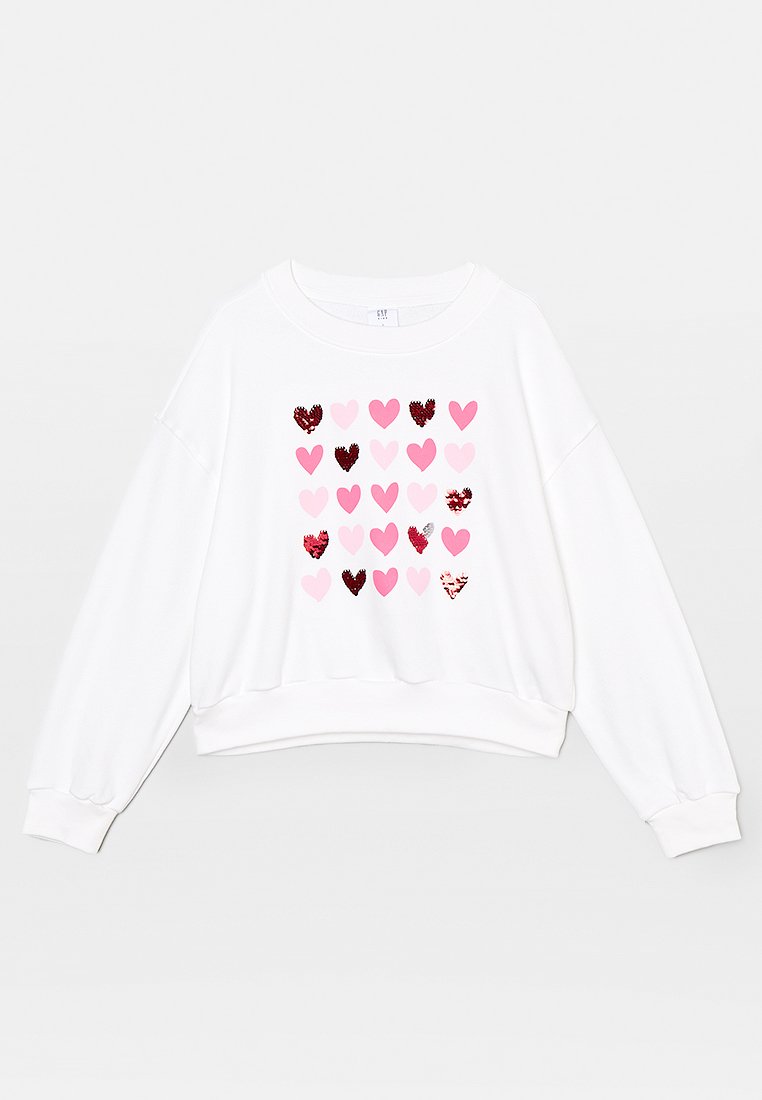 Weißes Sweatshirt mit langen Ärmeln und Rundhalsausschnitt, vorne in der Mitte mit einem Raster aus pinken und roten Herzen, von denen einige mit glänzenden Pailletten verziert sind.