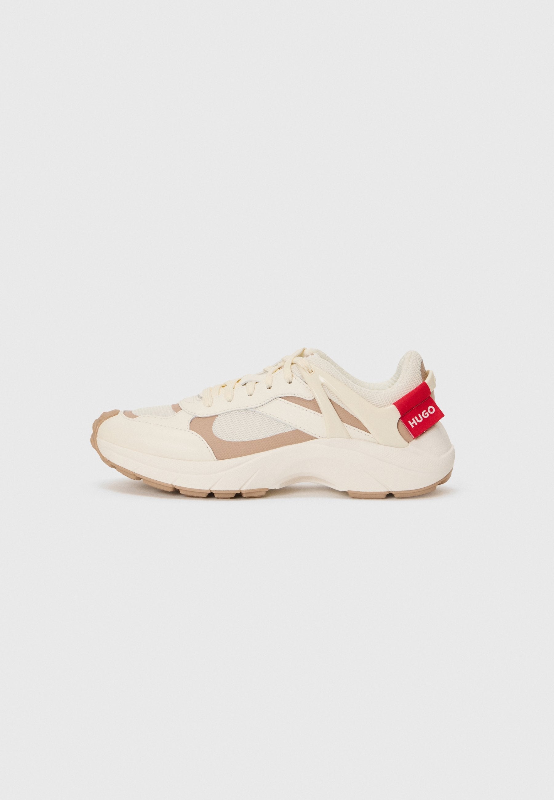 Cremfarbene und beige Sneaker mit einem strukturierten Netz-Obermaterial, Gummisohle und roter Markenkennung an der Ferse. Verfügt über Schnürsenkel und ein kontrastierendes Paneeldesign.