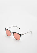Schwarzmetallic gerahmte Sonnenbrille mit pink getönten Gläsern, mit einer Katzenaugenform und schlanken Bügeln. Auffälliges Branding auf dem Rahmen.