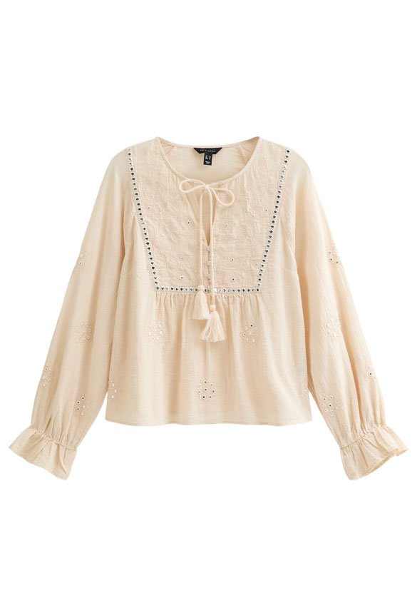 Cremefarbenes Blusenshirt mit langen Ärmeln, bestickten Details, rundem Ausschnitt, Zugband und Quastenakzenten. Gerafft an der Taille.