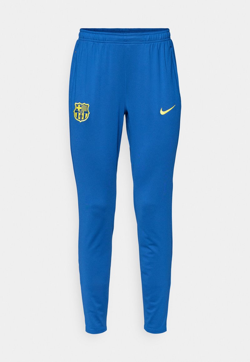 Blaue Sporthosen aus glattem Material, mit einem gelben Nike-Logo und einem Logo eines Fußballvereins auf dem linken Oberschenkel. Schmal zulaufendes Design.