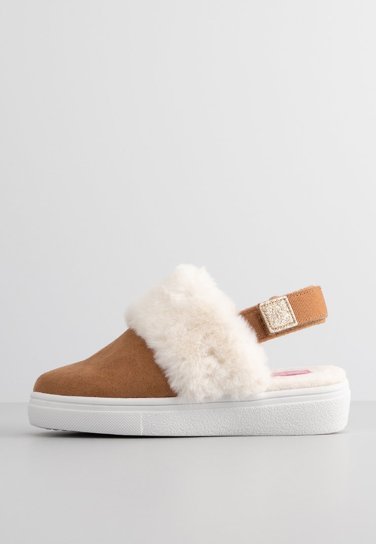 Braune Wildleder-Slipper mit weißer strukturierter Sohle, ausgestattet mit einem flauschigen cremefarbenen Fellband und einem sicheren, verstellbaren Riemen mit einer dekorativen Schnalle.