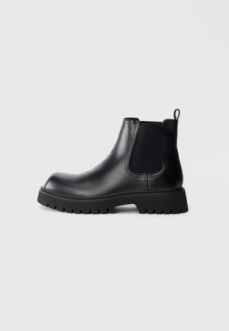 Schwarzer Chelsea-Stiefel aus Gummi mit glatter Oberfläche, elastischen Seitenteilen, einer Schlaufe zum Anziehen und einer robusten, profilierten Sohle für guten Halt.