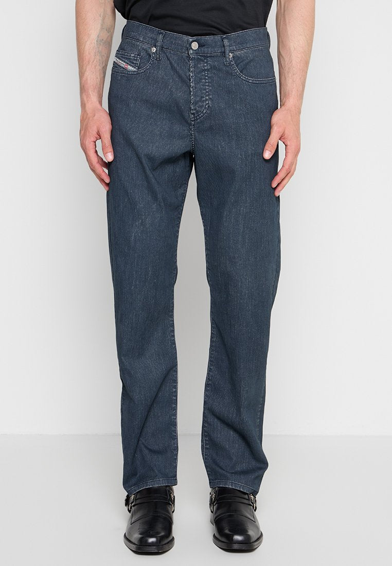 Dunkelblaue Jeans mit geradem Schnitt, getragen mit schwarzen Lederschuhen mit Schnalle, dargestellt von der Taille bis zu den Füßen vor einem schlichten hellen Hintergrund.
