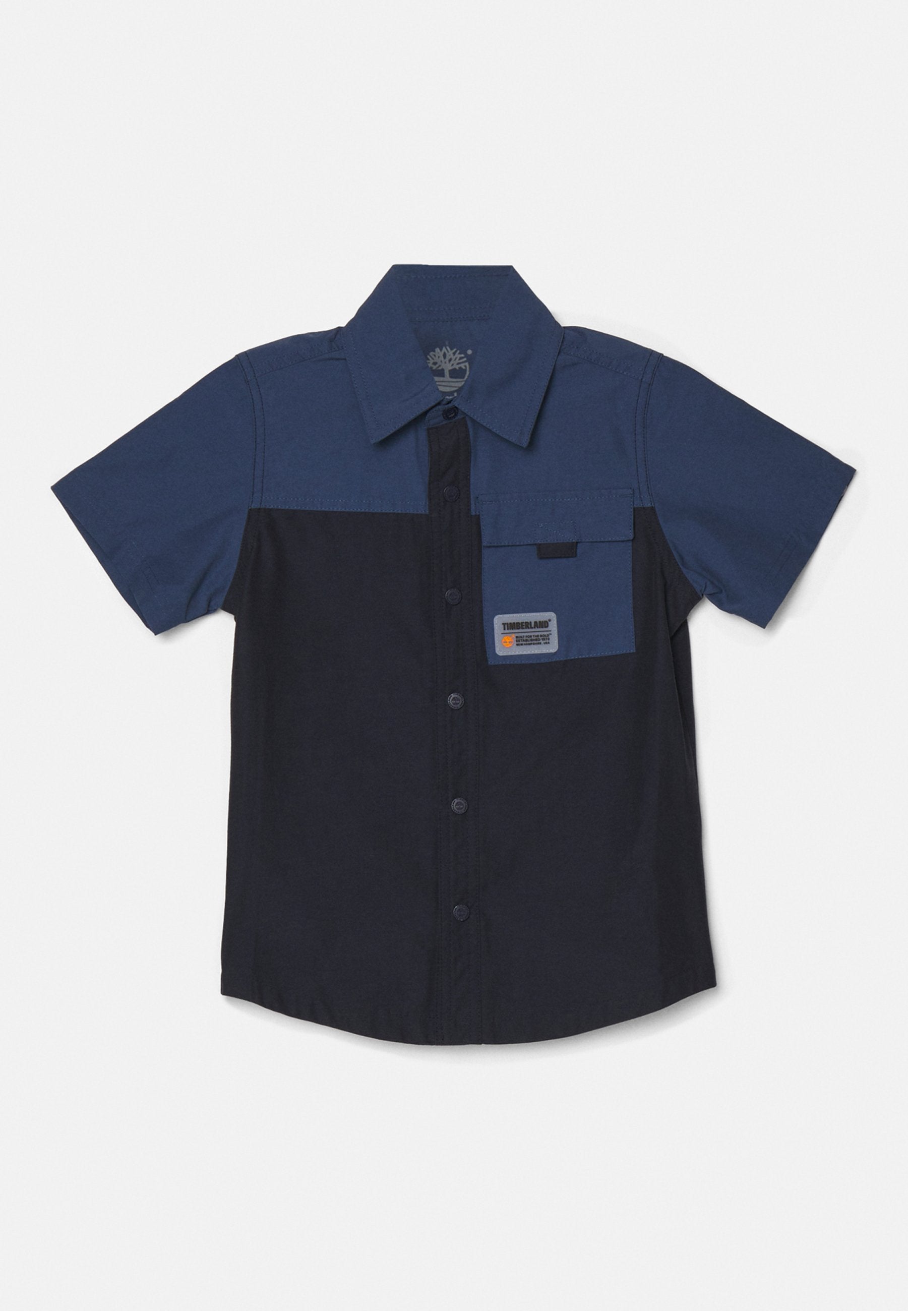 Kurzarm-Hemd aus dunkelblauem und marineblauem Baumwollstoff, mit einer Brusttasche mit Etikett und kontrastierenden Farbblocks.