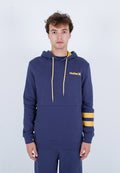 Junger Mann trägt einen marineblauen Kapuzenpullover mit gelben Kordeln, gelben Streifen am linken Ärmel und dem "Hurley"-Logo auf der Brust.