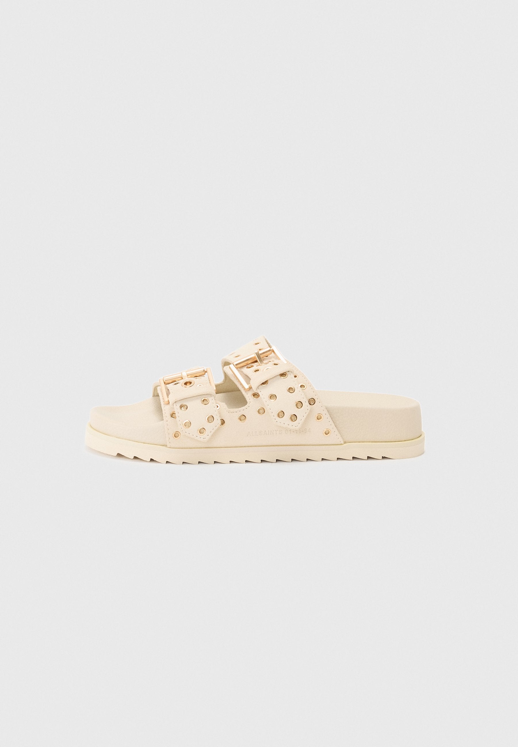 Beige Rutschsandalen mit doppelten Schnallenriemen, Nietenakzenten, flacher Gummisohle und strukturiertem Finish. Entwickelt für den Freizeitgebrauch.