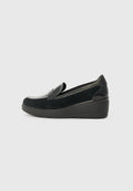 Schwarzer Wildleder-Slipper mit glänzendem schwarzen Lacklederakzent, Keilsohle und einem glatten, abgerundeten Zehendesign.