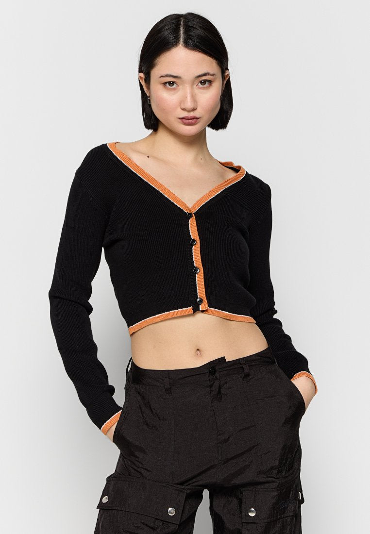 Schwarze, gerippte, cropped Strickjacke mit orangefarbenen Akzenten am V-Ausschnitt und der Knopfleiste. Verfügt über lange Ärmel und eine figurnahe Passform.