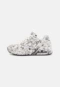 Weiße Sneaker mit schwarzen abstrakten Kritzeleien, Schnürdesign, gepolstertem Schaftrand und einer schwarzen Gummisohle mit sichtbarem Luftpolster.
