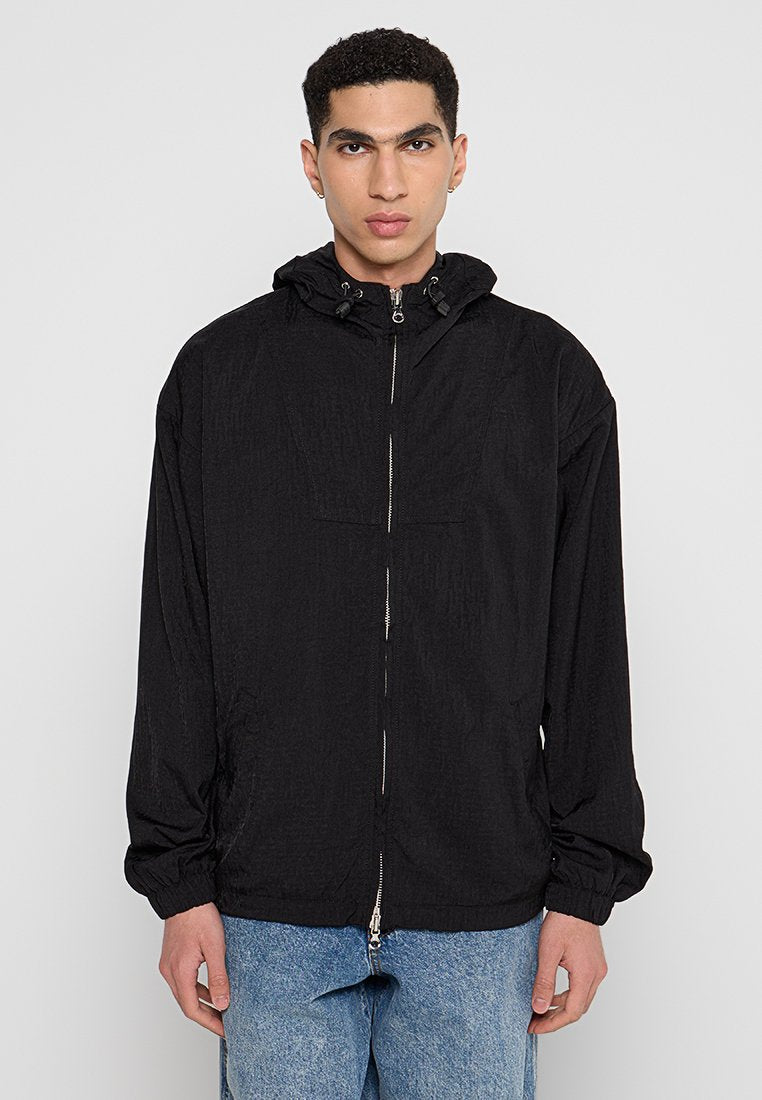 Schwarze leichte Jacke mit Kapuze, Frontreißverschluss, elastischen Bündchen und glatter Textur. Hat ein einfaches Design ohne sichtbare Muster.