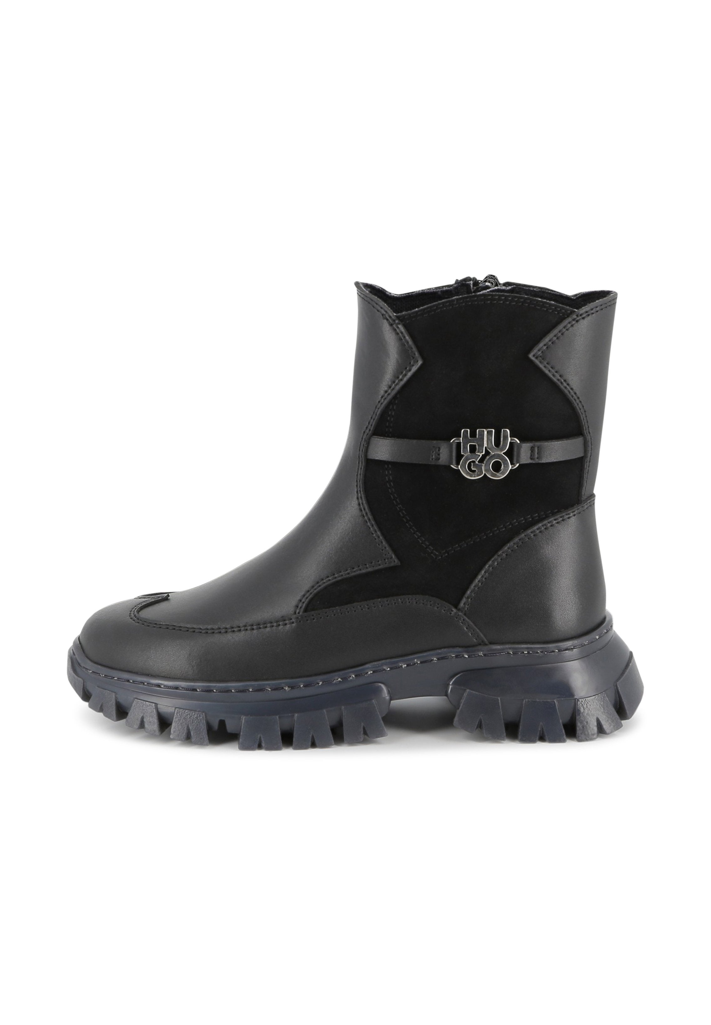 Schwarze Stiefeletten aus glattem Leder und Wildleder mit einer robusten Gummisohle, die einen dekorativen Logo-Riemen an der Seite haben.