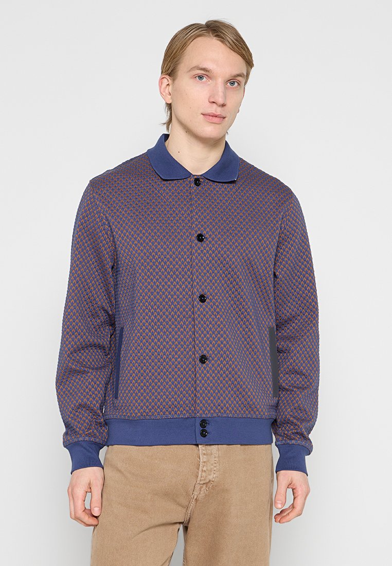 Marineblauer Cardigan mit Rautenmuster, Knopfleiste und kontrastierendem Kragen. Verfügt über zwei Seitentaschen sowie gerippte Bündchen und Saum.