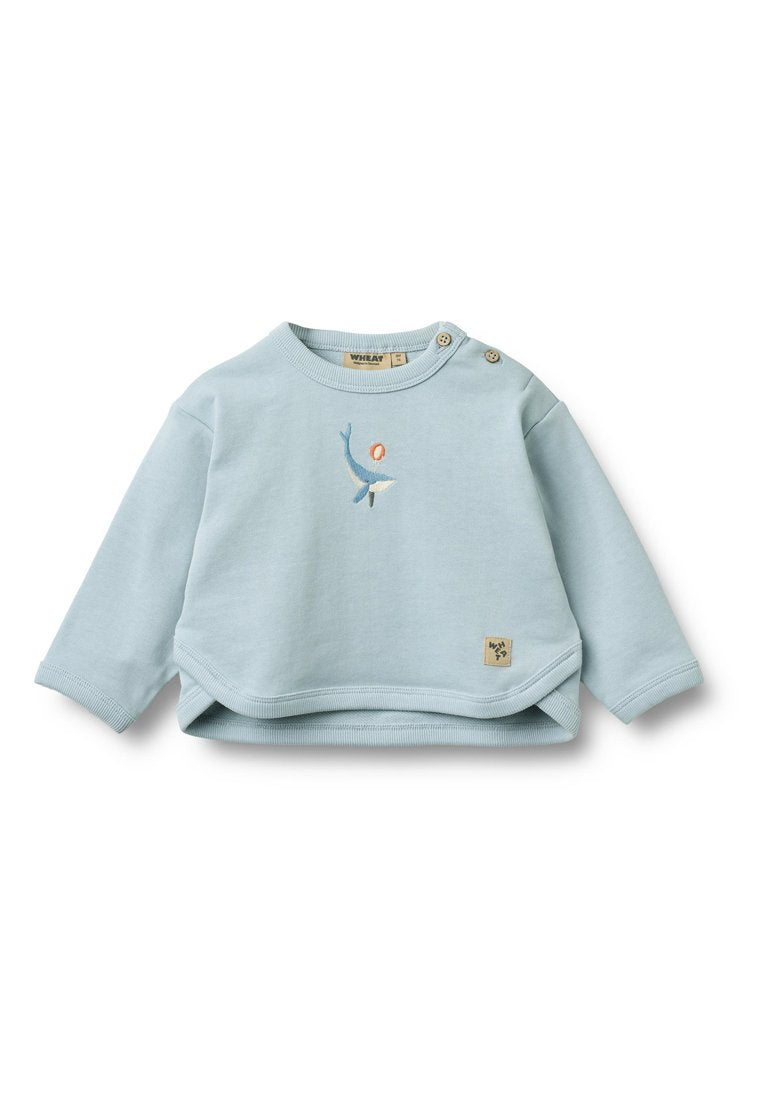 Hellblaues Baumwoll-Sweatshirt mit langen Ärmeln, gerippten Bündchen und zwei Knöpfen an der Schulter. Mit einem gestickten Fisch-Design und einem Label versehen.