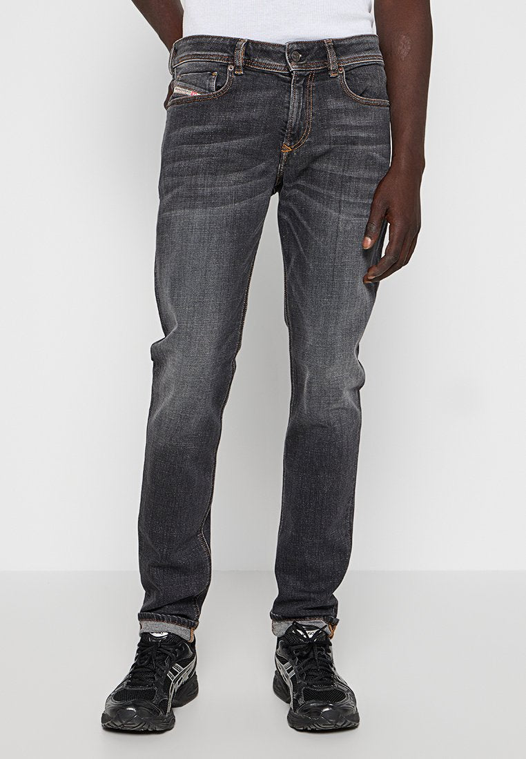 Dunkelblaue Jeans im Slim-Fit, mit orangefarbenen Nähten, einem klassischen Fünf-Taschen-Design und leichter Ausbleichung an den Oberschenkeln.