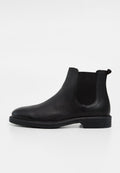 Schwarzer Leder-Chelsea-Boot mit elastischen Seitenteilen, niedrigem Absatz und Zuglasche auf glattem weißen Hintergrund.