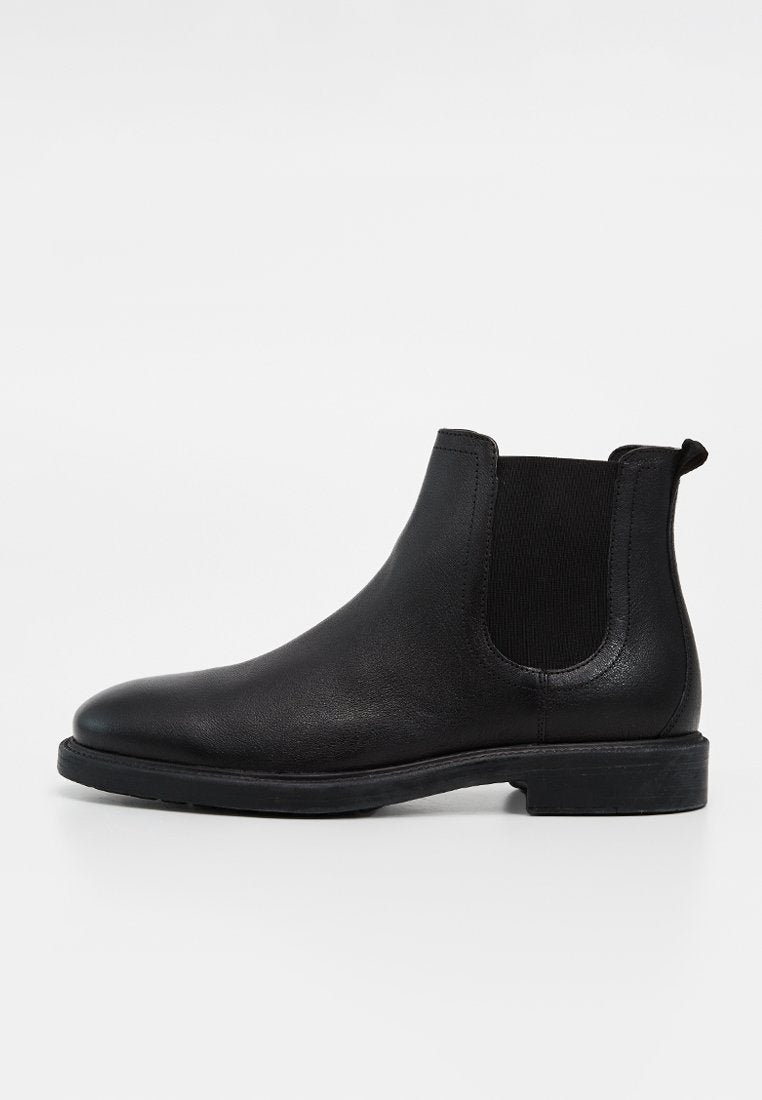 Schwarzer Leder-Chelsea-Boot mit elastischen Seitenteilen, niedrigem Absatz und Zuglasche auf glattem weißen Hintergrund.