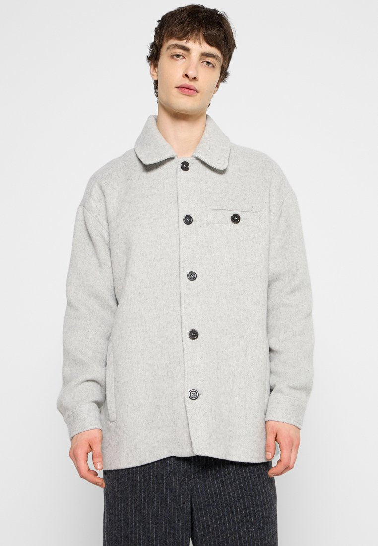 Hellgraue Wollmischung Jacke mit spitzem Kragen, vorderem Knopfverschluss, zwei Seitentaschen und einer Brusttasche. Schwarze Knöpfe sorgen für einen Kontrast.
