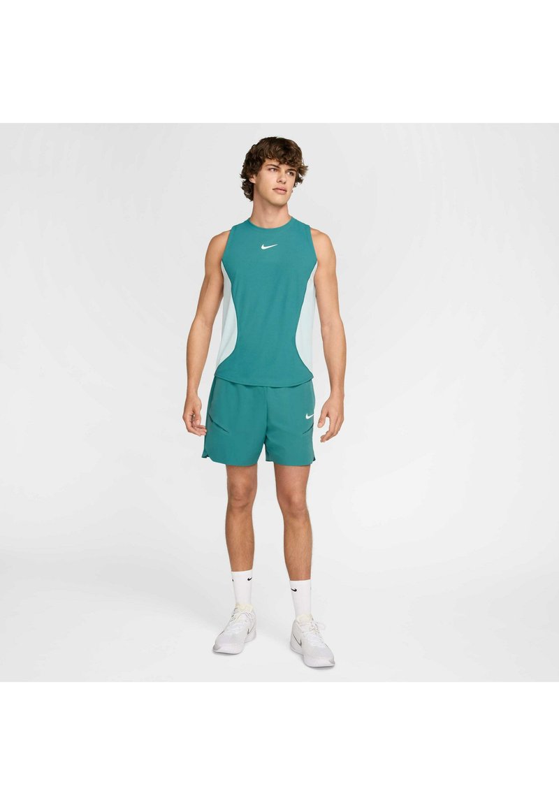 Teal Sport-Outfit bestehend aus einem ärmellosen Top und Shorts, mit weißen Seitenelementen und einem kleinen Logo. Hergestellt aus glattem, atmungsaktivem Stoff.