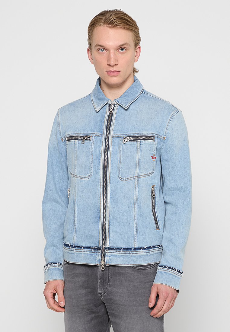Hellblaues Denim-Jackett mit Reißverschluss, zwei Brusttaschen und Seitentaschen. Merkmale einen verfransten Saum und kontrastierende Bündchen. Glatte Textur.