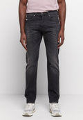 Schwarze Denim-Jeans mit geradem Bein, leichter Ausbleichung, fünf Taschen und einem kleinen Logopatch hinten. Kombiniert mit grauen Sneakers.