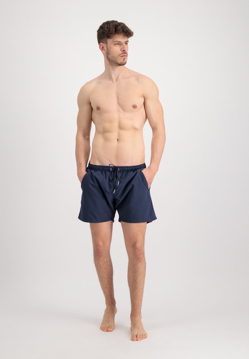 Marineblaue Badeshorts mit elastischem Bund und Kordelzug. Verfügt über Seitentaschen und einen glatten, leichten Stoff.
