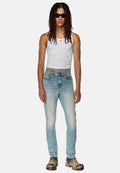 Hellblaue Denim-Jeans mit leichter Abnutzung, kombiniert mit einem eng anliegenden weißen Tanktop und schwarzen Sonnenbrillen. Klobige, gemusterte Schuhe runden den Look ab.