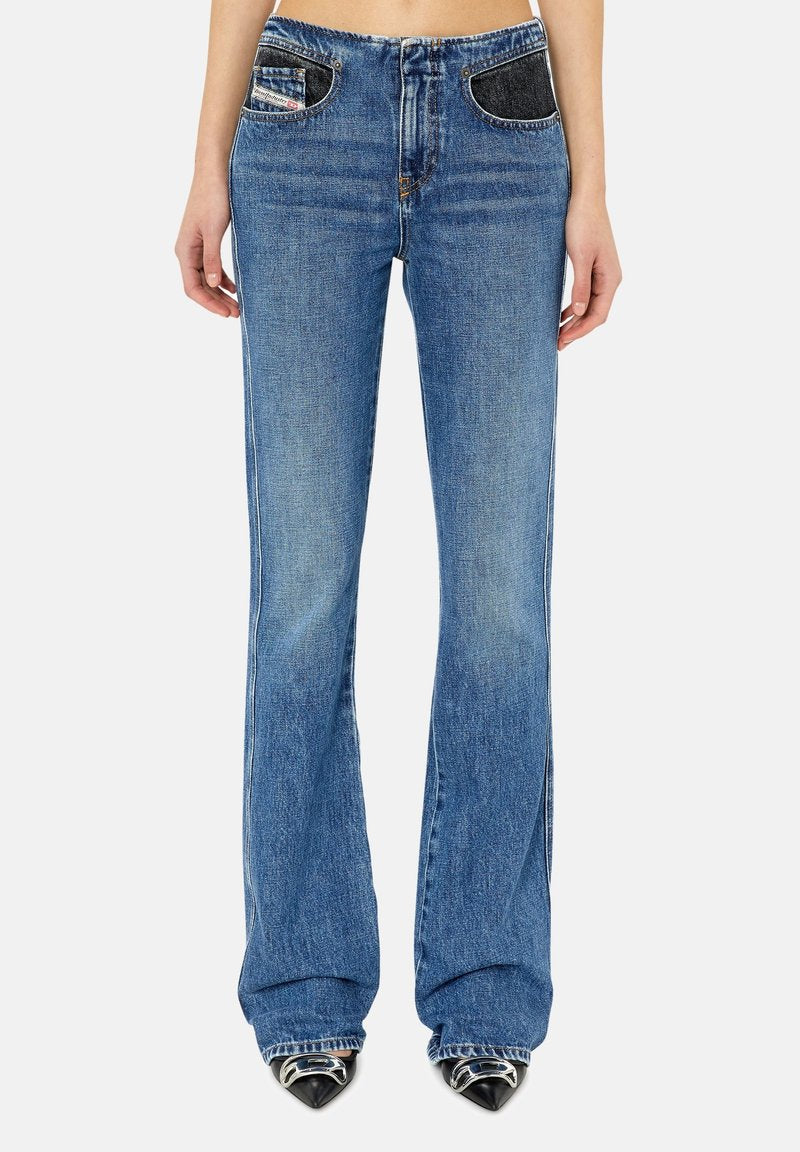 Eng anatomisch geschnittene blaue Jeans aus Denim mit ausgestellter Form, versehen mit dunklen Denim-Taschenakzenten und einem klassischen Knopfverschluss. Sie haben eine zerstörte Textur nahe dem Saum.