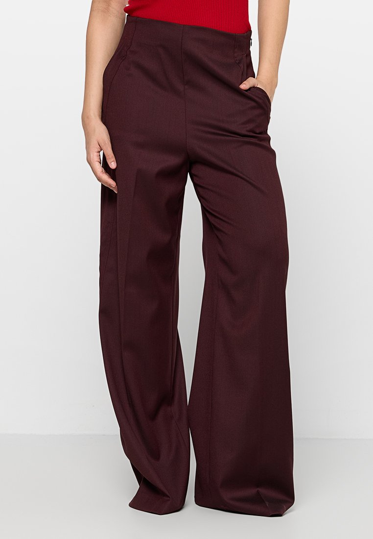 Burgunderfarbene weit geschnittene Hose aus glattem Stoff, mit Seitentaschen und maßgeschneidertem Design für eine entspannte Passform.