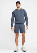 Marineblaues Sport-Sweatshirt mit Rundhalsausschnitt, kombiniert mit passenden Shorts. Begleitet von einer blauen Cap und cremefarbenen Sneakers mit dunklen Akzenten.