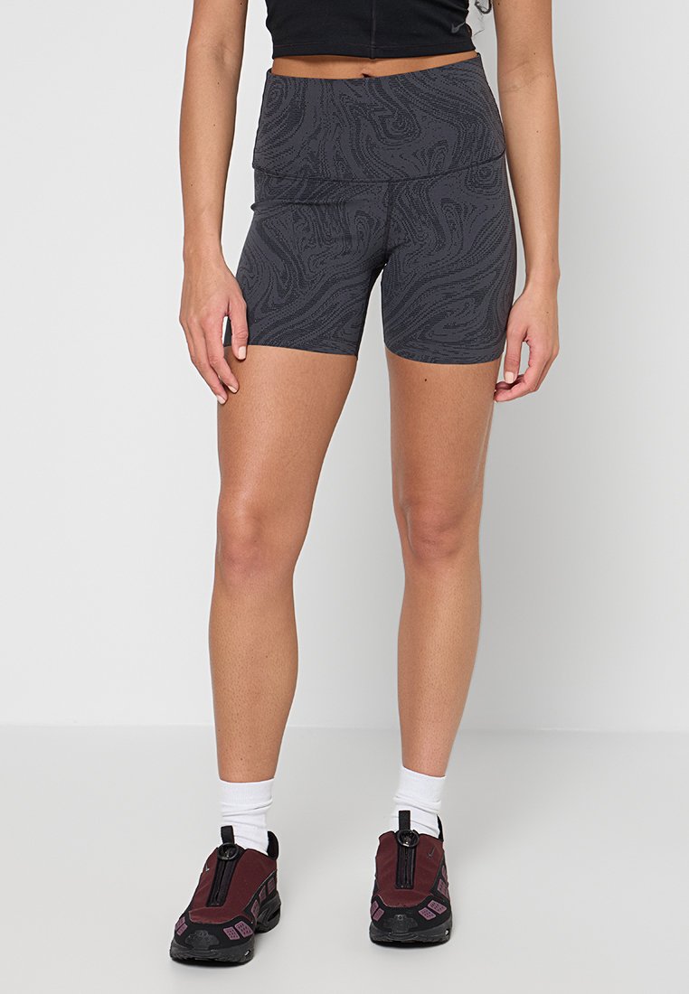 Graue gemusterte Shorts mit einem breiten Bund, aus einem dehnbaren Material gefertigt. Kombiniert mit burgunderroten Schuhen und weißen Socken.