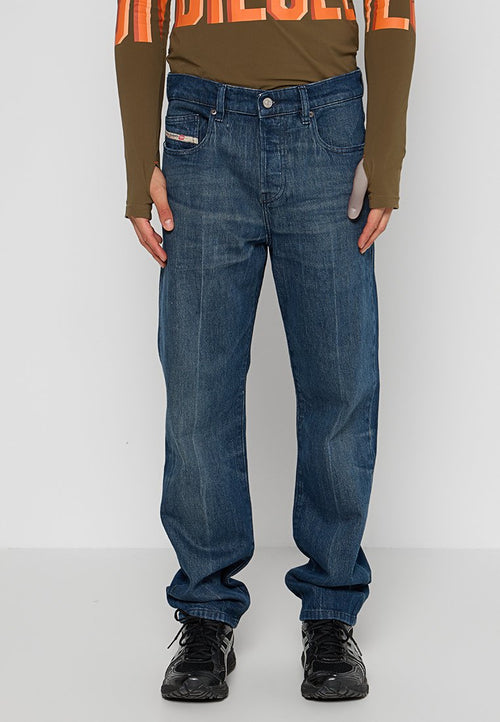 Dunkelblaue Denim-Jeans mit geradem Bein, Fünf-Taschen-Design und leichter Ausbleichung. Kombiniert mit einem olivfarbenen Langarmoberteil und schwarzen Sneakers.