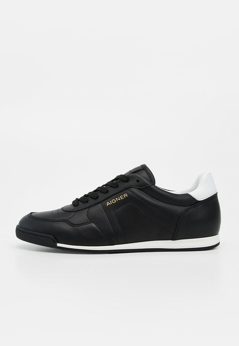 Schwarzer Low-Top-Sneaker mit weißem Fersenlasche, schwarzen Schnürsenkeln, dezenten Perforierungen und goldenem „Aigner“-Logo an der Seite.