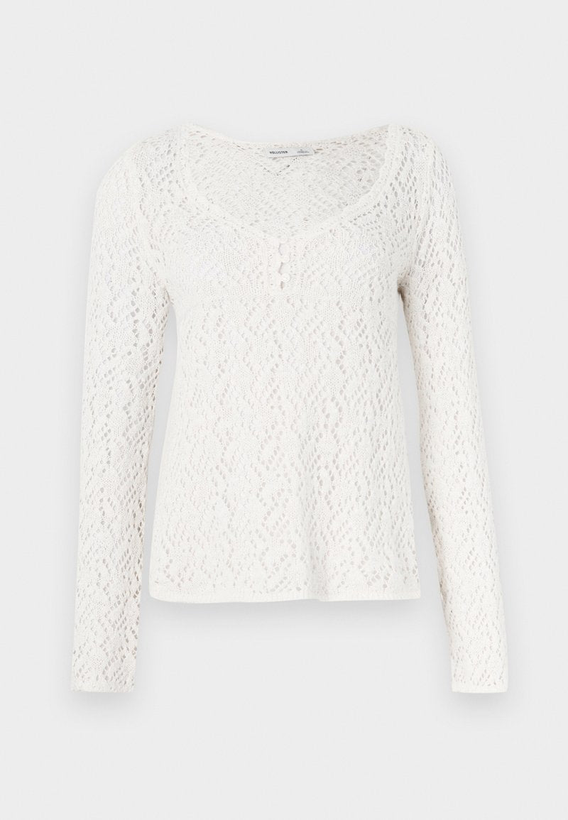 Weißes Spitzen-Longsleeve mit rundem Ausschnitt, verziert mit einem strukturierten Diamantmuster und kleinen Knöpfen entlang der Vorderseite.