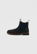 Schwarzer Chelsea-Stiefel mit marineblauen seitlichen Elastikeinsätzen, brauner Kappnaht, Zuglaschen vorne und hinten sowie niedrigem, gestapeltem Absatz auf weißem Hintergrund.