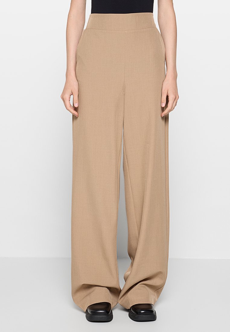 Beige weit geschnittene Hose mit glatter Textur, hoher Taille und taillierter Passform. Merkmale ein sauberes Design ohne zusätzliche Verzierungen.