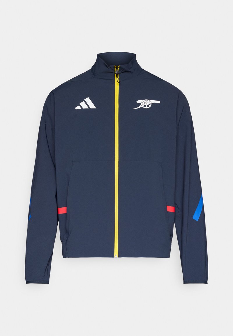 Marineblauer Reißverschlussjacke aus leichtem Material; verfügt über weißes Logo und Akzente in Rot und Blau, mit gelbem Reißverschluss und Stehkragen.