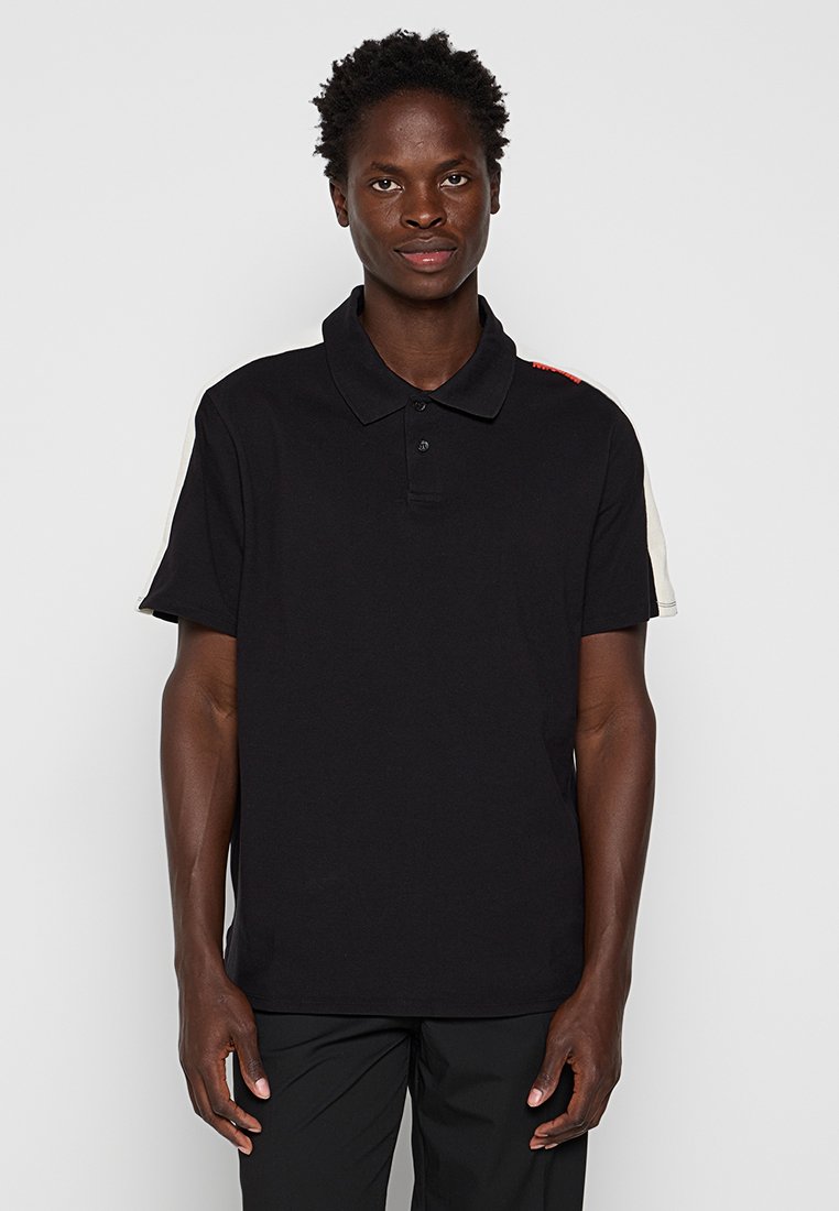 Schwarzes Poloshirt mit kurzen Ärmeln, mit einem einfarbigen Körper und cremefarbenen Akzenten an den Schultern, gefertigt aus weichem Baumwollmaterial.