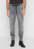 Graue Denim-Jogginghosen mit elastischem Bund, verstellbarem Kordelzug, Taschen vorne und schmalem Schnitt, kombiniert mit schwarzen Reißverschluss-Ankle-Boots.