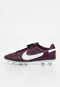 Lila Leder-Nike-Fußballschuh mit weißem Swoosh, schwarzen Schnürsenkeln und klaren Stollen auf einer weißen Sohle vor einfachem Hintergrund.