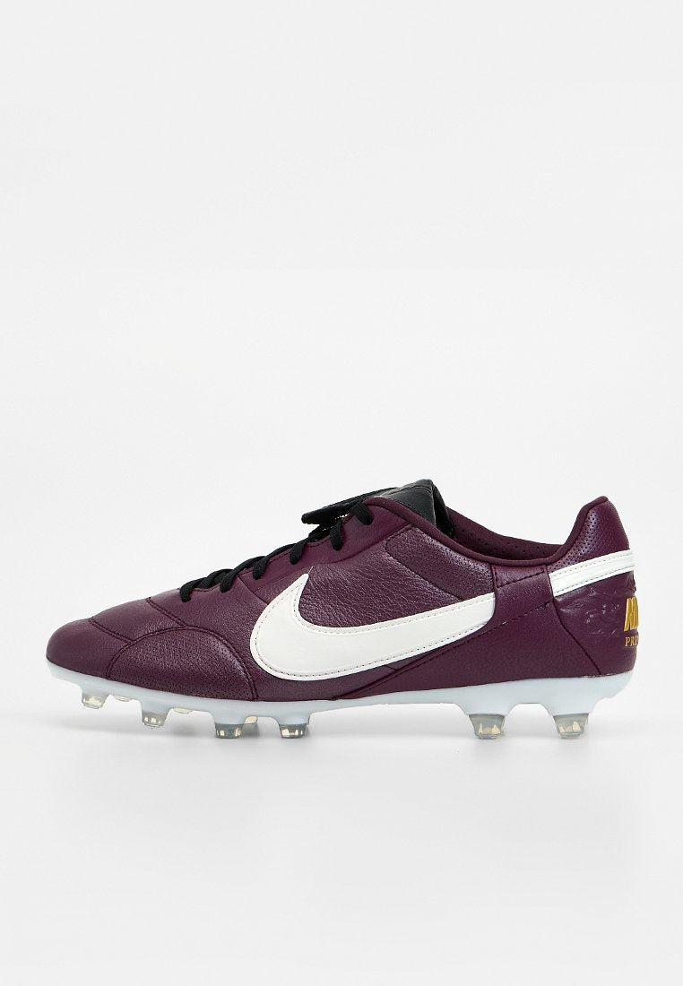 Lila Leder-Nike-Fußballschuh mit weißem Swoosh, schwarzen Schnürsenkeln und klaren Stollen auf einer weißen Sohle vor einfachem Hintergrund.
