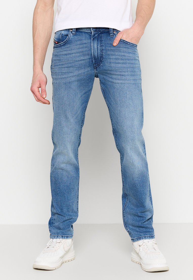 Helle blaue Denim-Jeans mit geradem Schnitt, ausgebleichtem Finish und klassischem Fünf-Taschen-Design. Getragen mit weißen Sneakers.