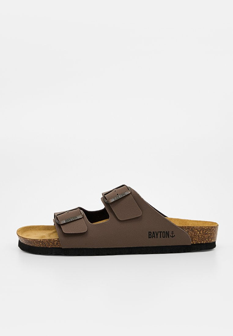 Braune Slide-Sandale mit zwei verstellbaren Riemen, Korkfußbett, schwarzer Sohle und Bayton-Logo an der Seite und am Riemen.