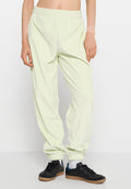 Hellgrüne, weiche Sweatpants aus Stoff mit einem elastischen Bund, gerippten Bündchen und einem weißen Logodetail. Getragen mit schwarzen Sportschuhen.