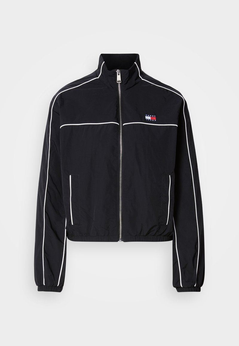 Schwarze, kürzere Jacke mit weißen Paspeln, ausgestattet mit einem hohen Kragen, Reißverschluss vorne und kleinem Logo auf der Brust. Hergestellt aus leichtem Stoff.