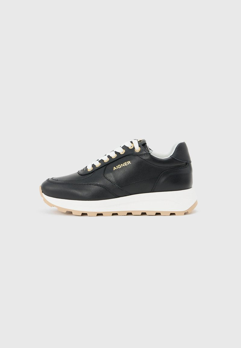 Schwarzer Ledersneaker mit weißen Schnürsenkeln, dicker weißer Sohle, beigem Profil und goldenem "AIGNER"-Logo an der Seite, seitlich dargestellt.