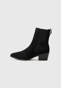 Schwarze Wildleder-Ankle-Boots mit spitzem Zehenbereich, elastischem Seitenpanel, Zugschlaufe und Blockabsatz auf einem schlichten weißen Hintergrund.