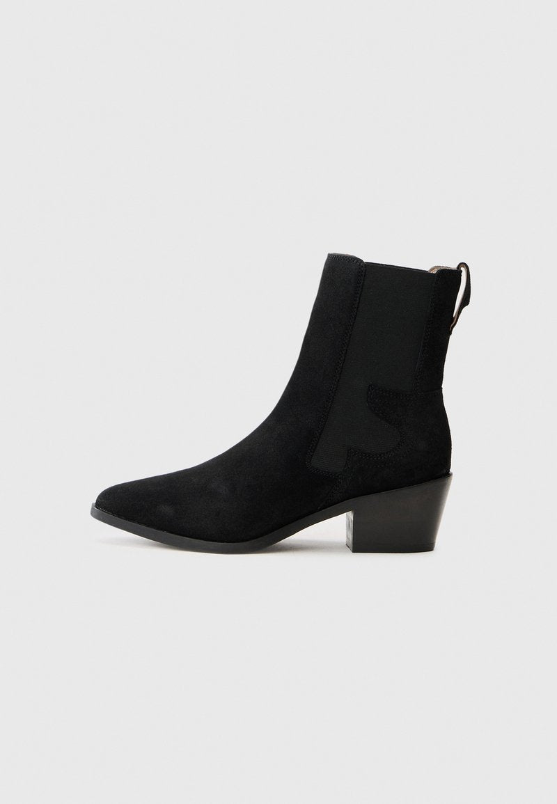 Schwarze Wildleder-Ankle-Boots mit spitzem Zehenbereich, elastischem Seitenpanel, Zugschlaufe und Blockabsatz auf einem schlichten weißen Hintergrund.
